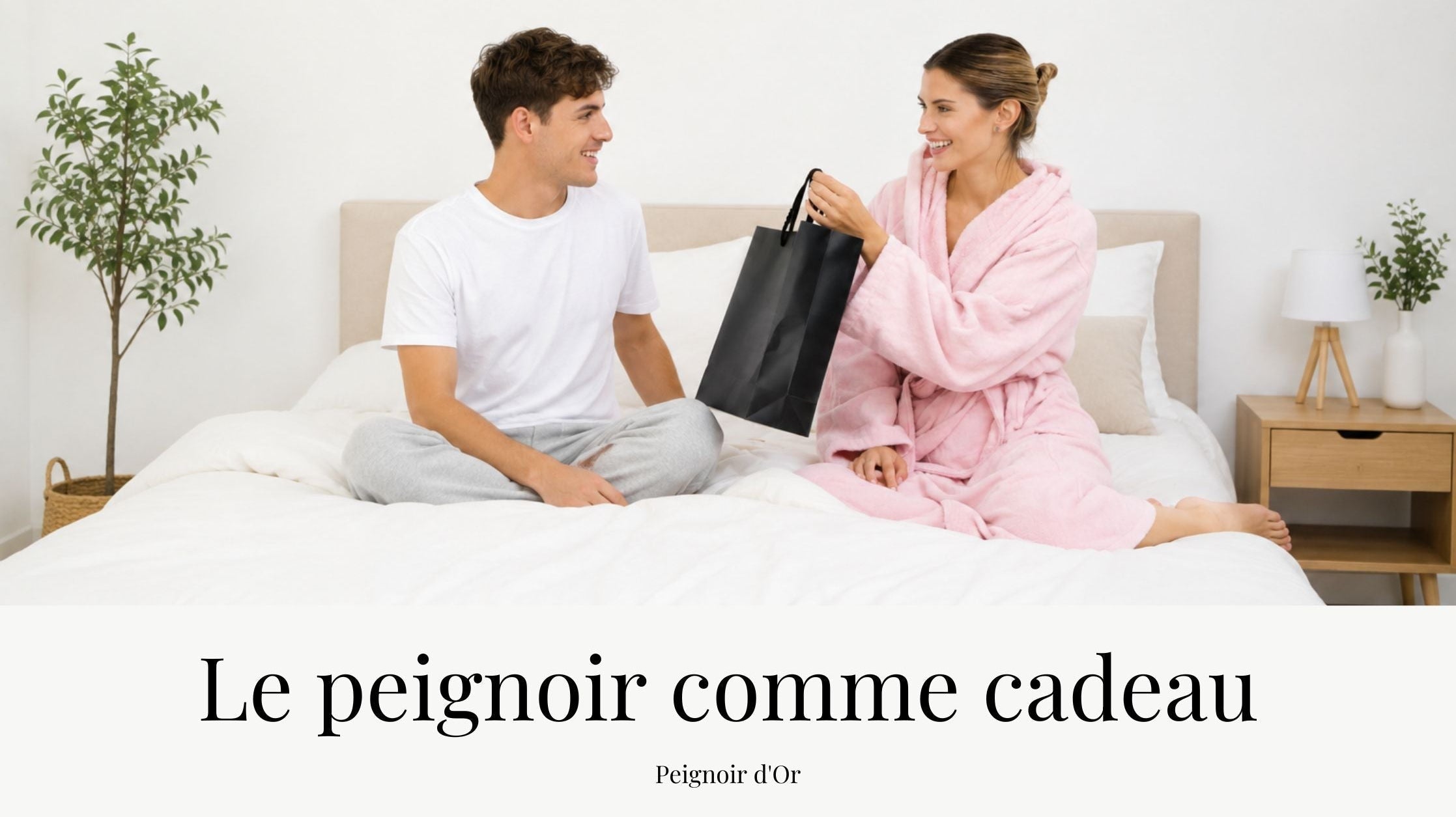 Homme offrant un cadeau à une femme portant un peignoir rose sur un lit dans une chambre lumineuse, illustrant une idée cadeau de peignoir pour femme dans un univers cocooning.