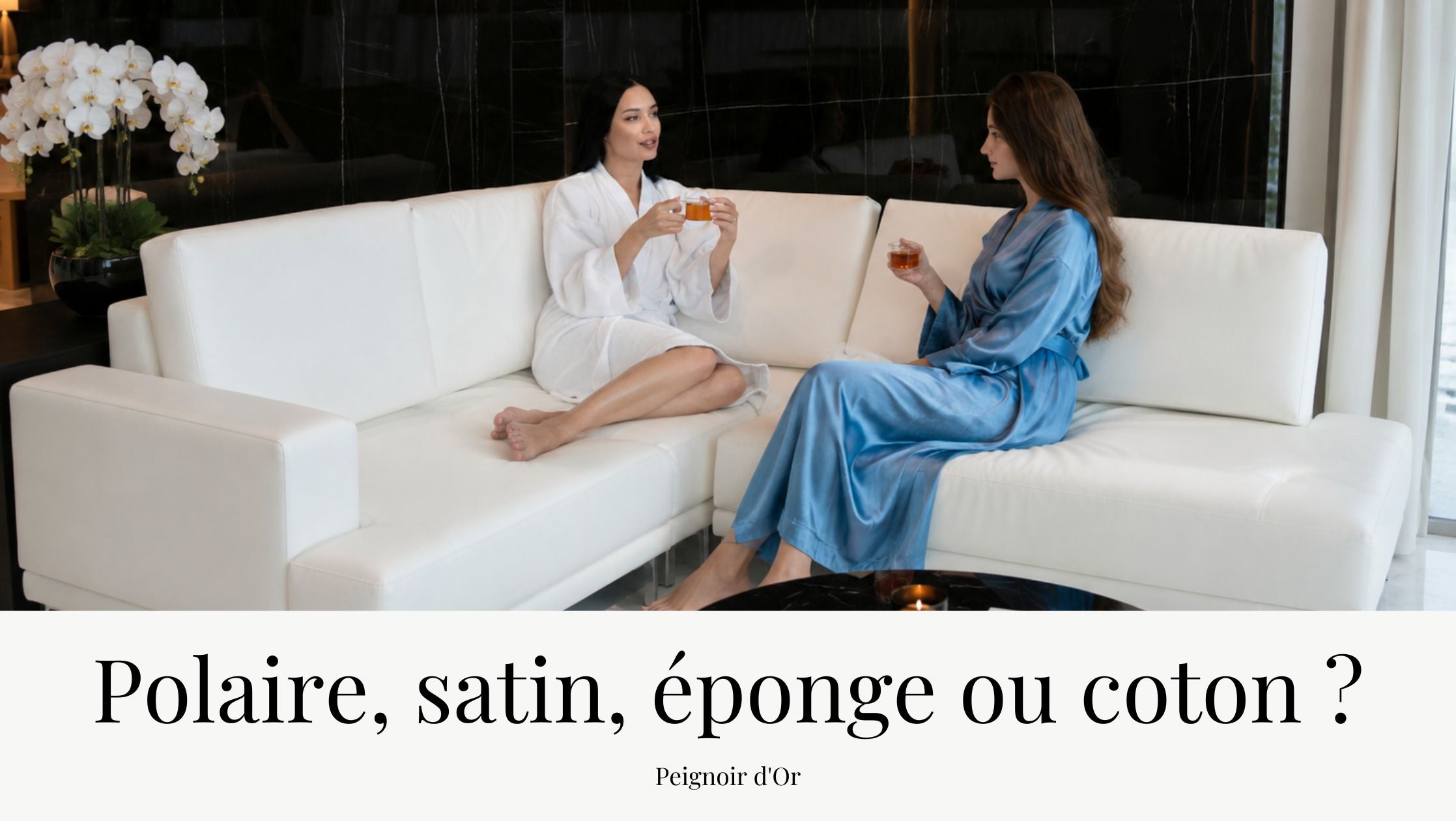 Deux femmes en peignoir, l'une en éponge blanche et l'autre en satin bleu, discutent autour d'une tasse de thé dans un élégant espace bien-être au design moderne.