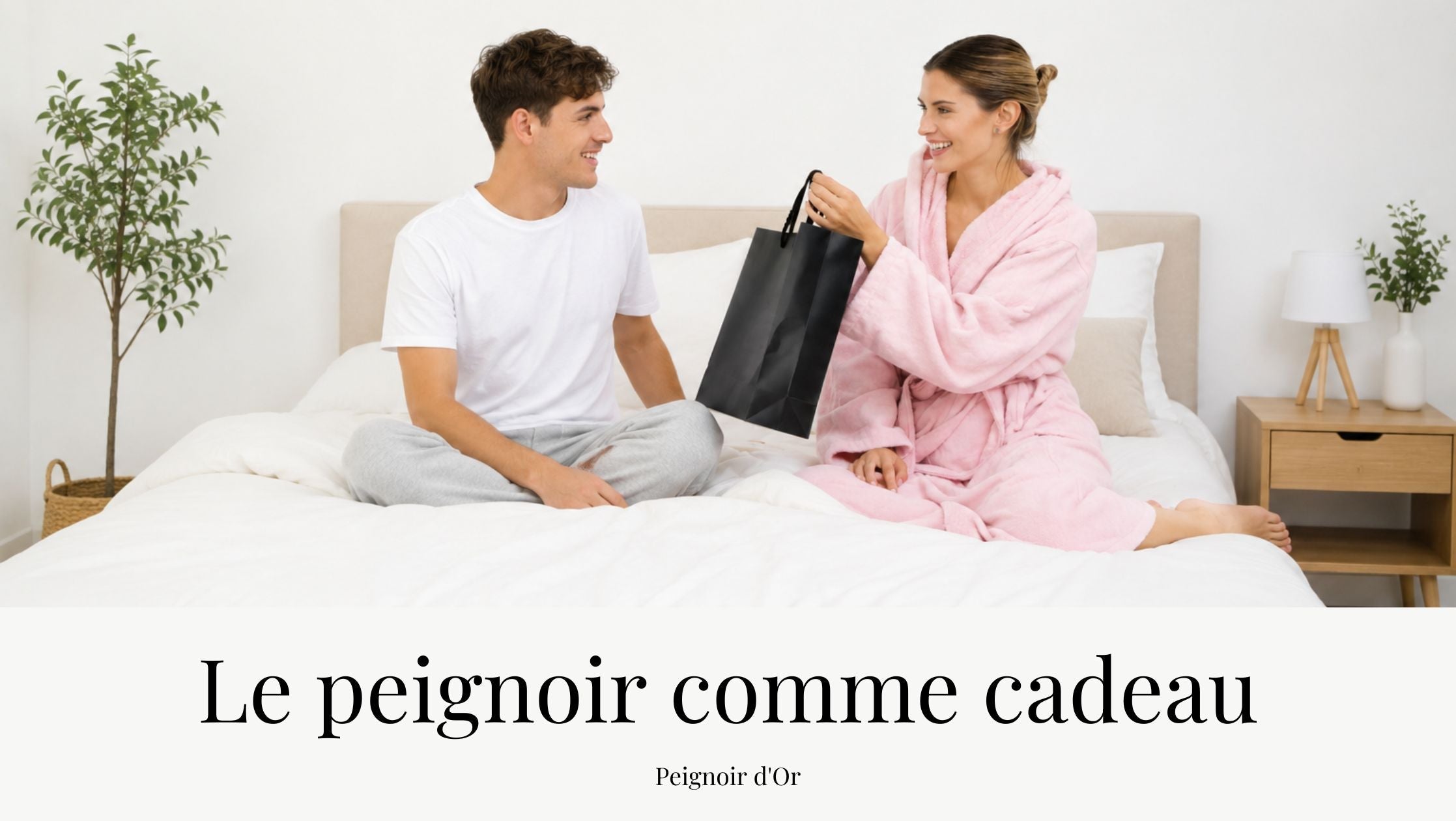Homme offrant un cadeau à une femme portant un peignoir rose sur un lit dans une chambre lumineuse, illustrant une idée cadeau de peignoir pour femme dans un univers cocooning.